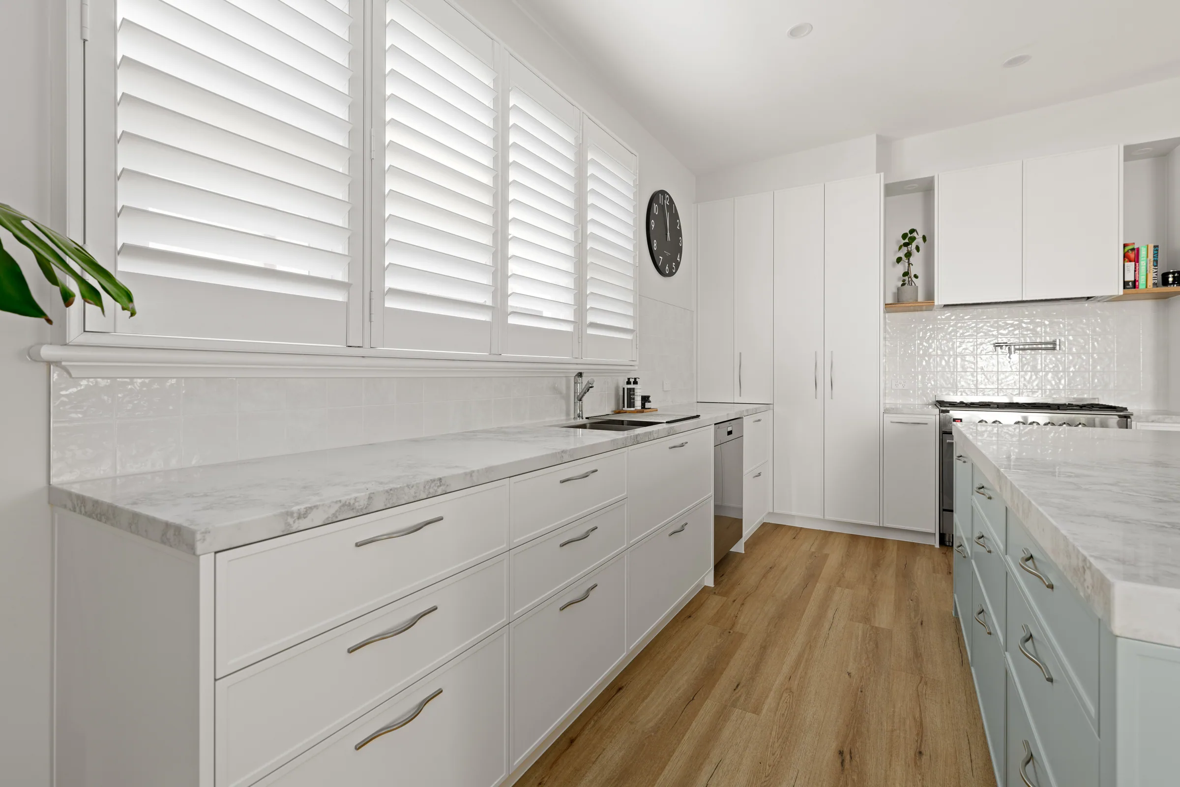 White drawer bank with curved metal handles under a marble-look benchtop, gloss white tiled splashback and sage island drawers at right.